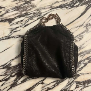 Svart axelväska från Stella McCartney - Säljer min Stella McCartney väska då jag inte har använt den på 1 år! Den har inte kommit till andvänding, ordinarie pris är 9 tusen men eftersom den är lite rostig vid handtaget så säljer jag den för 3500! Skit snygg när man ska ut!❤️pris kan diskuteras! 