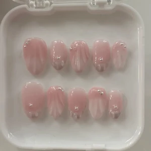 Rosa lösnaglar med pärldekoration - Snygga rosa lösnaglar med en mjuk ombre-effekt och dekorerade med små pärlor och stjärnor. Perfekt för en elegant look. Naglarna kommer i en praktisk förpackning.