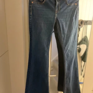 Blå bootcut jeans från H&M - Snygga blå bootcut jeans från H&M. De har en klassisk femficksdesign och är perfekta för en avslappnad stil. Jeansen har en bekväm passform och är tillverkade i ett slitstarkt denimtyg.