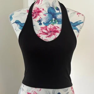 Svart halterneck topp - snygg svart halterneck topp med ärmlös design. toppen är croppad och passar utmärkt till både jeans och kjol!! 