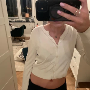 Vit kofta från HM - Säljer en vit  kofta med knappar framtill. Koftan har långa ärmar och är perfekt för en stilren look. Passar bra till både jeans och kjol. Perfekt för vår och sommar! En liten defekt på armen! 