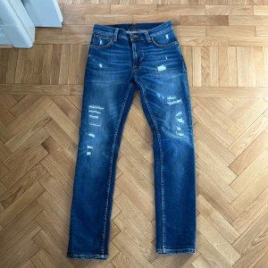 Nudie Jeans - Säljer dessa sjukt snygga Nudie Jeans med coola slitningar. De är i modellen Thin Finn, storlek W29 L32. Skick:10/10 aldrig använda, utan prislapp. Nypris ligger runt 2000kr. Hör av er vid frågor eller funderingar!