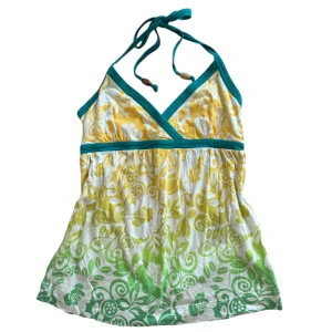 Gul och grön halterneck topp - Säljer en färgglad halterneck topp med ett vackert blommönster i gult och grönt. Toppen har en omlott-design och knytband i nacken med dekorativa träpärlor. Perfekt för sommarens varma dagar!
