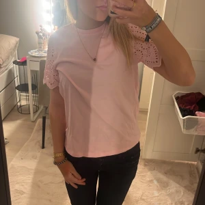 Rosa topp från ONLY - Säljer en söt rosa topp från ONLY med korta ärmar i spets. Perfekt för en avslappnad stil med en touch av elegans. Toppen har en rund halsringning och är gjord i ett mjukt material.