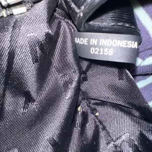 Svart axelväska från DKNY - Snygg svart axelväska från DKNY i 100% skinn. Väskan har en stilren design med silverdetaljer och en praktisk dragkedja. Perfekt för att bära dina dagliga nödvändigheter med stil.