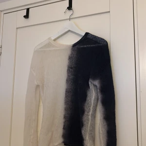 Svart och vit tröja från Weekday - Snygg svart och vit tröja från Weekday med ett unikt färgblocksmönster. Tröjan har en långärmad design och är tillverkad i ett lätt och transparent material. Perfekt för en stilren och modern look.