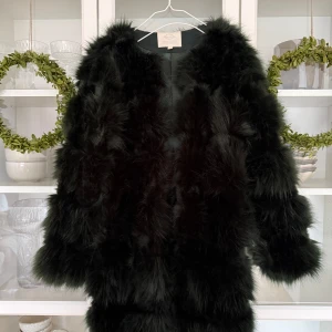 Mörkgrön pälsjacka (faux fur) - Säljer en mörkgrön pälsjacka med långärmad design. Köpt för flera år sedan i en butik på drottningggatan i Stockholm. Själva fakepälsen är i nyskick men själva hakfästet som man stänger på insidan på jackan är sönder (en liten hake som man hakar fast, inte någon kedja). Storlek 34-36.