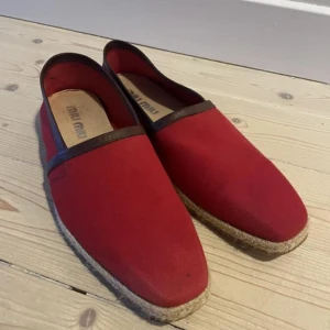 Miu Miu Röda espadrillos  - Snygga röda espadrillos från Miu Miu med bruna detaljer. Skorna har en klassisk design med en sula i repmaterial som ger en somrig känsla. Perfekta för en avslappnad stil.