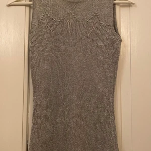 Grå glittrig topp - Snygg glittrig topp med stickat mönster och dekorativa detaljer vid halsen. Superfint skick med en defekt/litet hål på bild 3💞