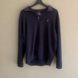 Svart tröja från Polo Ralph Lauren - Säljer en stilren navy blue tröja från Polo Ralph Lauren med dragkedja vid halsen och det klassiska logotypbroderiet på bröstet. Perfekt för en avslappnad och snygg look.