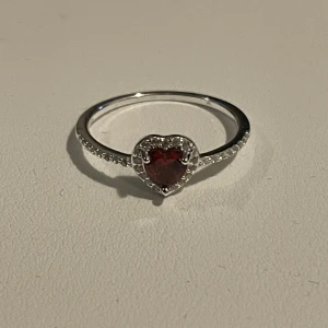 Sterling Silver Ring - Köpte på Glitter för ett tag sedan, jag tror inte de säljer den här färgen längre. Aldrig använd, den är helt ny och den kommer utan ask.  Det är sterling silver 925 med en rödformad Cubic Zirconia hjärtsten med små stenar runt den.  På Glitters hemsida står det storlek 18, vilket betyder 18 mm.
