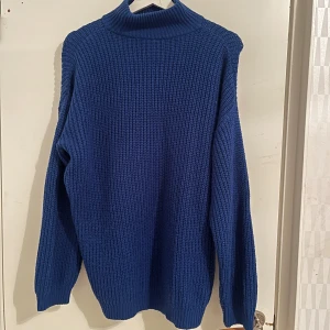 Blå stickad polotröja från H&M Divided - Säljer en snygg blå stickad polotröja från H&M Divided. Perfekt för kyliga dagar med sin höga krage och långa ärmar. Tröjan har en klassisk design som passar till många olika stilar. Ett måste i garderoben för den som älskar stickade plagg!