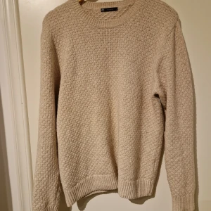Beige stickad tröja från Cellbes - Säljer en stilren beige stickad tröja från Cellbes. Tröjan har en rund halsringning och långa ärmar med ribbade muddar. Perfekt för kyligare dagar och ger en klassisk look.