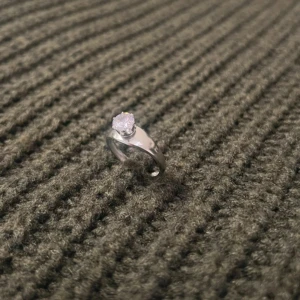 Oval Essence - Silver Ring with Stone - US storlek 7, diameter 17,3 mm, omkrets 54,4 mm. Med sitt platta band och unika ovala design utstrålar denna ring modern elegans. Den gnistrande stenen och den justerbara passformen gör den både stilren och bekväm.