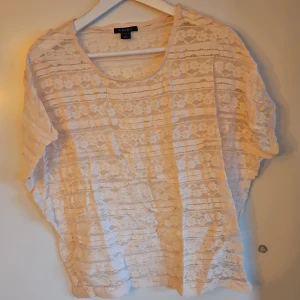 Ljus rosa spetsblus - Säljer en söt ljus rosa spetsblus. Blusen har korta ärmar och ett blommigt mönster. Perfekt för en somrig look! 🌸