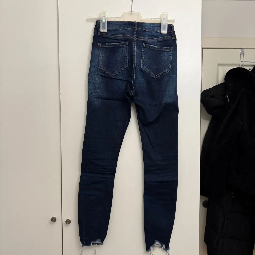 Snygga mörkblå jeans från Levis med en tight passform och slitna detaljer vid bensluten. Perfekta för en trendig look. Klassisk femficksdesign och knappgylf.. Farkut & Housut.