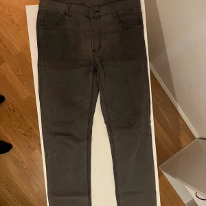 Grå jeans från Cheap Monday - Snygga grå jeans från Cheap Monday med en klassisk femficksdesign. De har en knappgylf och en stilren look som passar perfekt till vardags. Märkets ikoniska logga syns på baksidan. 34/34