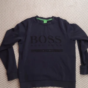 Svart tröja från Hugo Boss - Säljer en stilren svart tröja från Hugo Boss med deras logga tryckt på framsidan. Tröjan har en slim fit passform och långa ärmar. Perfekt för en avslappnad men ändå snygg look. Hör av dig vid intresse! Priset kan diskuteras 