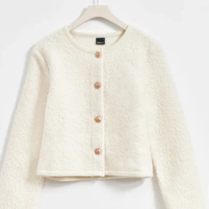 Vit teddyjacka med knappar - Mysig vit teddyjacka från ginatricot med rund hals och knappar framtill. Jackan har en fluffig textur och långa ärmar, perfekt för kyligare dagar. En stilren och bekväm jacka som ger en trendig look. 