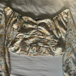 Långärmad blommig sommartopp  - En jättefin blus/topp köpt på BikBok för några år sedan, med perfekta balong armar och en jättefin urringning vid bröstet och i ryggen. Samt en liten volang vid magen som gör en perfket extra detalj, toppen är använd fåtal gånger och jag inga skador!