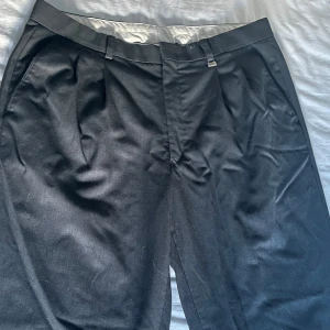 Mörkgråa baggy kostymbyxor  - Mörkgråa baggy kostymbyxor köpt i en butik utomlands. Sitter som en smäck och säljer endast för att jag inte har användning för dem längre! Jag är 172 och dom är långa på mig.  De har den perfekta baggy fitten men sitter fortfarande bra i midjan. 
