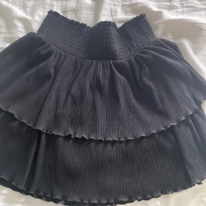 Svart volangkjol! - En jättefin volangkjol från Kappahl! Typ lite ribbad i materialet. Storlek 158/164!