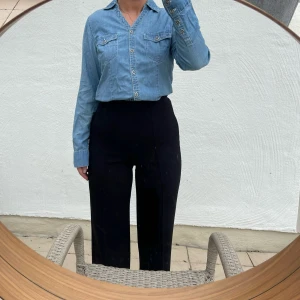 Jeansskjorta med knappar - Säljer en snygg jeansskjorta i klassisk blå denim. Skjortan har långa ärmar och knappar hela vägen fram. Väldigt liten i storleken. Perfekt för en avslappnad stil, oavsett om du bär den stängd eller öppen över en t-shirt.