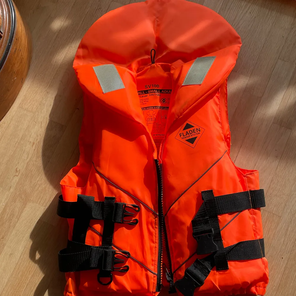 Säljer en knallorange flytväst från Fladen Rescue System. Den har en dragkedja framtill och justerbara svarta remmar för en säker passform. Västen är i storlek XS och passar vuxna med kroppsmassa mellan 40-50 kg. Perfekt för säkerhet på vattnet!. Jackor.