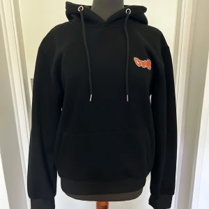 Off-white hoodie med tryck - Säljer denna svarta Off white hoddie. Den har en stor ficka fram och justerbar huva med snören. Perfekt för höst och vinter, och den är i nyskick. Trycket på ryggen är riktigt unikt med en orm mönster.