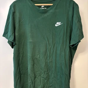 Grön t-shirt från Nike - Säljer en snygg grön t-shirt från Nike. Den har en klassisk rund hals och korta ärmar. Nike-loggan är tryckt i vitt på bröstet. Perfekt för vardagsbruk! Skick 9/10! Fler frågor hör av dig!