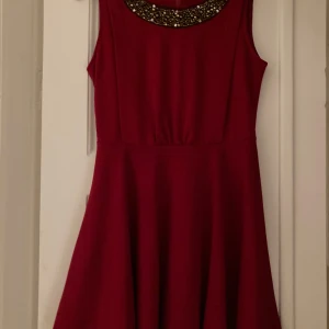 Festlig klänning  - Mörkröd klänning med pärldekorationer. Klockad kjol. Längd: 82 cm. Perfekt för julens fester🎉