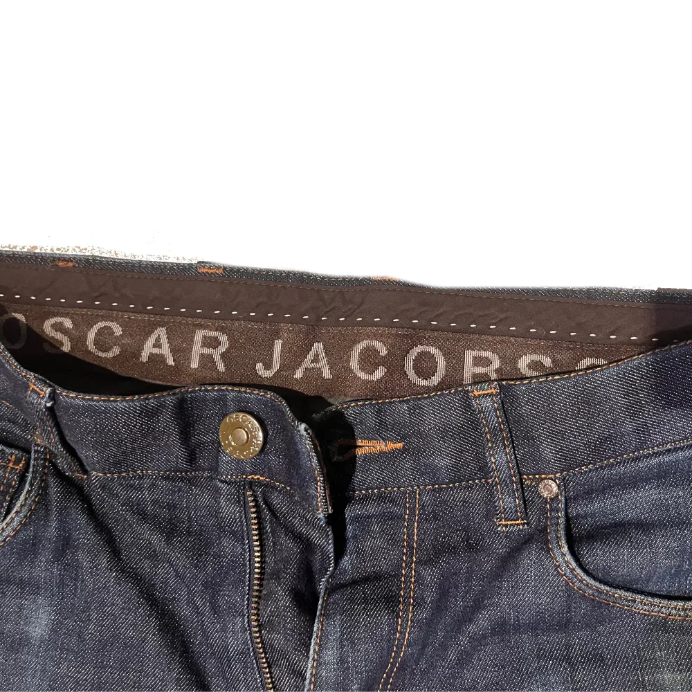 Säljer ett par snygga mörkblå jeans från Oscar Jacobson. De har en klassisk design med fem fickor och en knappgylf. Jeansen är i bra skick och har en stilren look som passar både till vardags och fest. Perfekta för höst och vinter!. Jeans & Byxor.