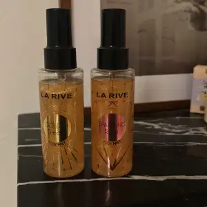 Två body mists från La Rive: Golden Dream och Sparkling Rose. Båda har en elegant design med svart spraykork och genomskinlig flaska. Golden Dream har en gyllene etikett medan Sparkling Rose har en rosa etikett. Perfekta för att fräscha upp sig med en lätt och behaglig doft.