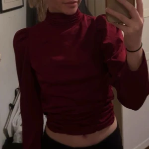 Vinröd topp med öppen rygg - Snygg vinröd topp med hög krage och långa ärmar. Den har en trendig öppen rygg och knytning i midjan, vilket ger en elegant touch. Perfekt för en utekväll eller fest! 💃Perfekt även till jul!! 