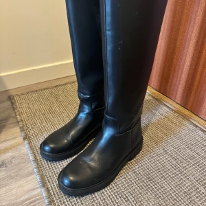 Svarta höga stövlar - Snygga svarta höga stövlar i skinn. Endast använd under ett tillfälle, köpt för en vecka sedan! Väldigt stor i storleken, passar mig som har 37.5 i vanliga fall