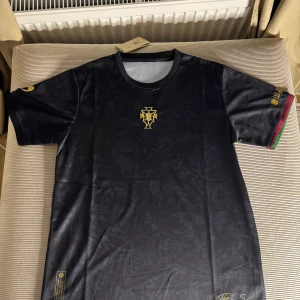 Ronaldo Siu GOAT limited edition  - , Legends Edition. Tröjan har korta ärmar med gulddetaljer och ett coolt emblem på bröstet. Ärmarna har även röd och grön kant. Perfekt för fotbollsfans som vill ha något unikt! 🖤
