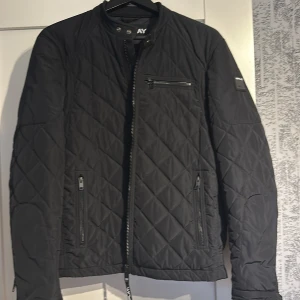 Svart quiltad jacka från Replay - Säljer en snygg svart quiltad jacka från Replay. Den har dragkedja fram och tre praktiska fickor med dragkedjor. Perfekt för höst och vår, med en stilren look som funkar till det mesta. Jackan är i mycket bra skick och har långa ärmar.