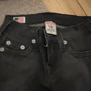 Svarta jeans med dragkedjor - Säljer ett par svarta jeans i bra skick. De har en tight passform och coola dragkedjor längst ner på benen. Perfekta för en rockig look eller en utekväll. De är högmidjade och har klassiska femfickor. Passar till både vardag och fest!