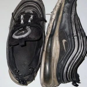 Svarta Nike sneakers - Säljer ett par svarta Nike sneakers i använt skick. De har en klassisk design med vita detaljer och synlig Air Max-sula. Perfekta för vardagsbruk men har  tecken på slitage. Passar bra för dig som gillar en avslappnad stil. Butiks pris 2000kr