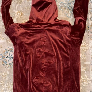 Röd sammetshoodie från Sean John - Säljer en supermjuk och snygg röd sammetshoodie från Sean John. Den har en stor ficka fram och en broderad logga på bröstet. Perfekt för att hålla sig varm och stilren under kyliga dagar. Passar både till vardags och chillkvällar. 🧡 perfekt för vintern och mysiga julen . Nypris 3000kr