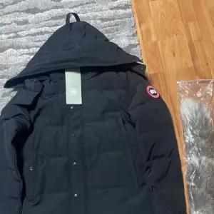 Säljer en svart Wyndham Parka från Canada Goose i nytt skick. Jackan är perfekt för vintern med sin varma och stilrena design. Den har en avtagbar huva och ikonisk logga på ärmen. Passar perfekt för kalla dagar och har en klassisk look. möts upp i göteborg