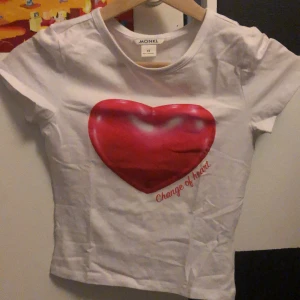 Vit t-shirt med hjärtmotiv från Monki - Jag säljer en vit t-shirt med ett rosa hjärta på framsidan. Det är en tight tröja från monki i storlek XS