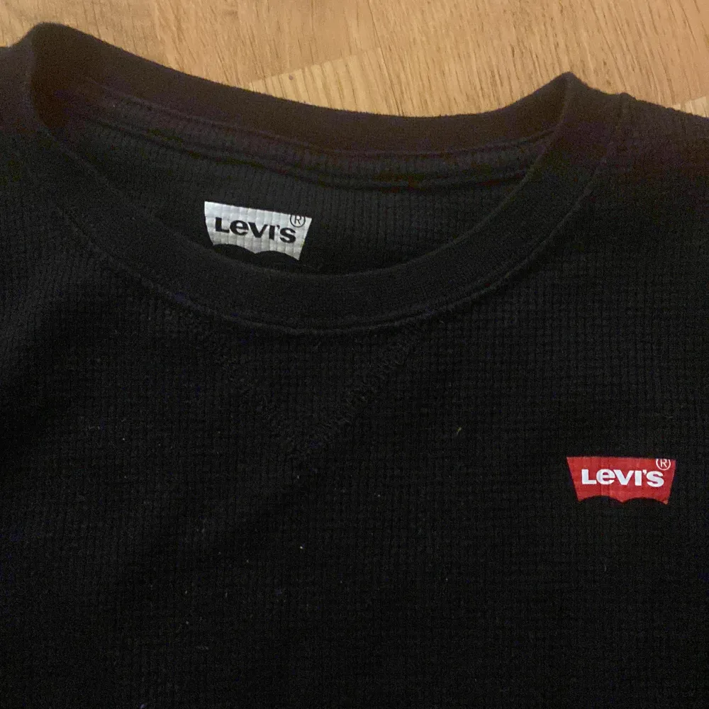 Säljer en svart långärmad tröja från Levi's i mycket bra skick. Tröjan är ribbad och har en liten röd Levi's-logga på bröstet. Perfekt för höst och vinter, och passar till både vardag och fest. Skön och stilren design!. Tröjor & Koftor.