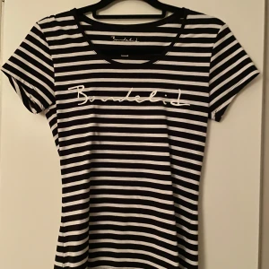 Randig t-shirt från Bondelid - Säljer en snygg randig t-shirt från Bondelid i svart och vit. Den har en klassisk rund hals och korta ärmar. Perfekt för en avslappnad stil eller sommarens äventyr. Passar bra till jeans eller shorts!