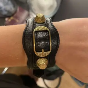 Säljer ett snyggt svart läderarmband från Balenciaga. Armbandet har guldfärgade detaljer och passar till allt!😇😇