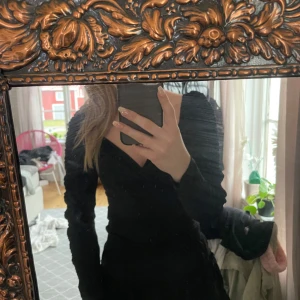 Svart topp med rynkade detaljer - Säljer en elegant svart topp med rynkade detaljer. Toppen har en figurnära passform och långa ärmar, Materialet känns mjukt och bekvämt mot huden.🖤🖤