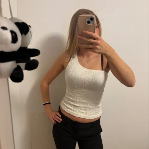 Vit ärmlös topp - Säljer en snygg vit ärmlös topp med ett subtilt mönster. Perfekt för sommardagar eller en utekväll. Toppen är tight och framhäver figuren på ett smickrande sätt. Passar bra till både jeans och kjol.