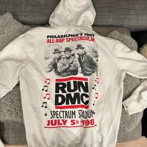 Säljer en vit hoodie från H&M med coolt RUN DMC-tryck. Perfekt för dig som älskar retro och hiphop! Den har en stor bild på baksidan och en mindre logga fram. Grym för både vardag och chill. 🕶️