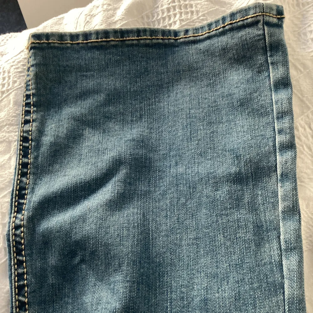 Säljer ett par snygga blå jeans från Lindex i ny skick. De har coola stjärndetaljer på bakfickorna och kontrastsömmar som ger en unik look. Perfekta för vardagsbruk eller en avslappnad utekväll. Passar bra till både sneakers och boots!Endast lite använda.. Jeans & Byxor.