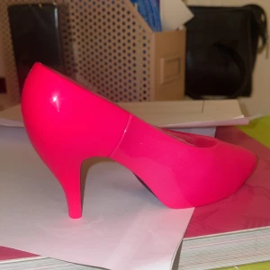 Neonrosa parfymflaska i form av en sko - En cool neonrosa parfymflaska formad som en högklackad sko. Doften heter 'Neon Nights Ibiza Pink' och har fruktiga, söta och blommiga toner med inslag av amber och tropiska noter. Perfekt för en utekväll eller fest! Ej använd, däremot har parfymen en liten repa på utsidan (se bild nmr 2) , men inget som påverkar parfymen i fråga!  Skulle säga att denna parfym passar alla, både vuxna och barn, beroende på vad man tycker om! 🥰 pris kan alltid diskuteras. 